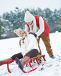 Mann schiebt Frau auf Schlitten im Schnee