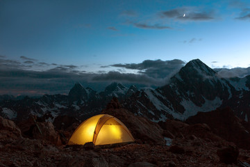 Wall Mural - Twilight Mountain Panorama and Tent Illuminated Camping Yellow Tent Night High Altitude Alpine Landscape Crescent in Dark Blue Sky warmer tone