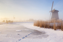 Dutch Windmills In A Foggy Winter Landscape In The Morning
