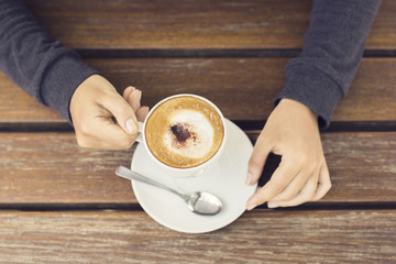 Wall Mural - Girl hands with cup of coffee on a wooden table