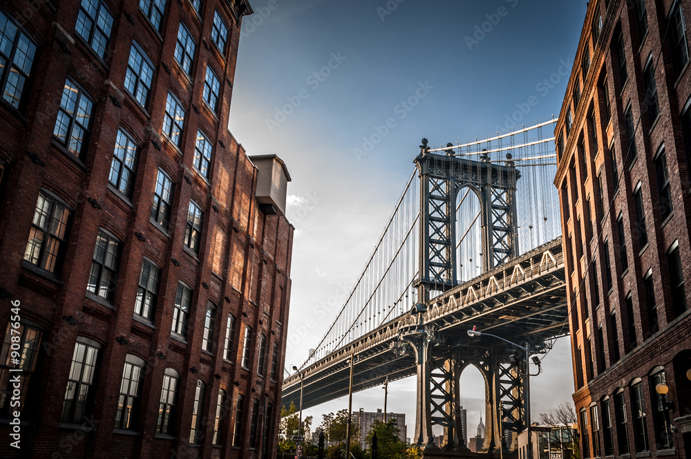Manhattan bridge seen from a narrow alley enclosed by two brick buildings on a sunny day in summer - obrazy, fototapety, plakaty 