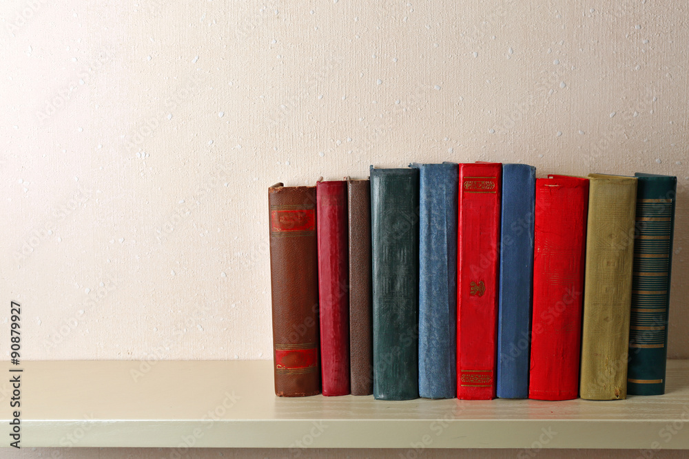 Old books on shelf, close-up, on light wall background