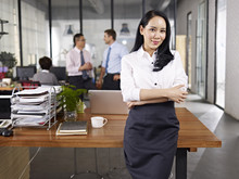 Portrait Of Young Asian Business Woman Standing In Office Arms Crossed