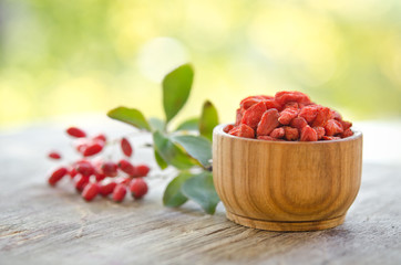 Wall Mural - berberries and goji berries isolated on wooden table.