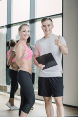 Sticker - smiling young woman with personal trainer in gym