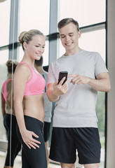 Wall Mural - smiling young woman with personal trainer in gym