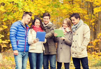 Wall Mural - group of smiling friends with tablets in park