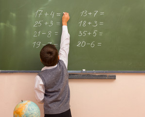 boy writes chalk on blackboard