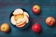 Red apples with slices over blue wooden background