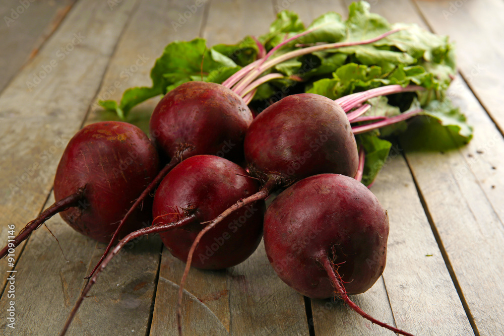 Young beets with leaves on wooden table close up