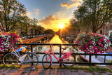 Fototapeta Zachód słońca - Beautiful sunrise over Amsterdam, The Netherlands, with flowers and bicycles on the bridge in spring