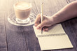 © pingpao - Woman hand writing on notebook over wooden table with coffee cup