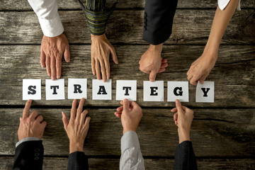 Top view of eight business people assembling the word STRATEGY