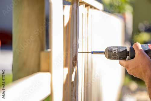 Man erecting a wooden fence outdoors Tableau sur Toile