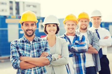 Wall Mural - group of smiling builders in hardhats outdoors