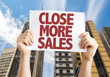 Close More Sales placard with cityscape background