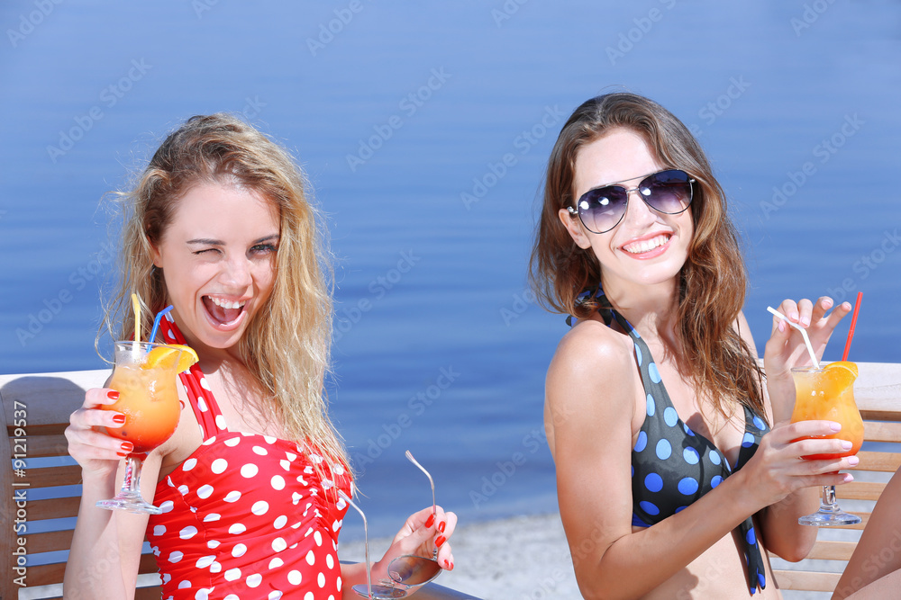Two young girls enjoying cocktails on beach