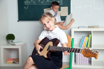 Wall Mural - Cute pupils having music lesson in classroom at elementary school