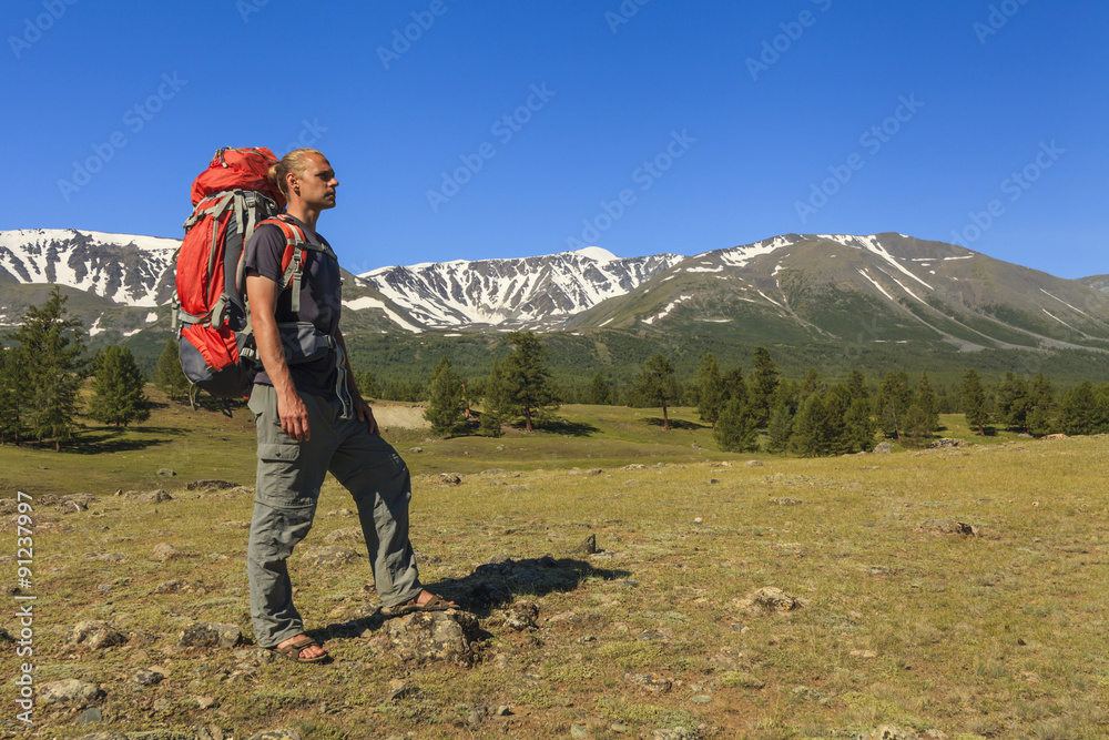 Young traveler with a backpack on the background of mountain sce - obrazy, fototapety, plakaty 