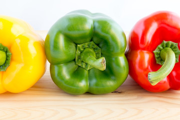 Three bell peppers in a row in different colours, yellow, green and red