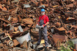 © sima - Recycling industry, worker stand at heap of old metal holding tube