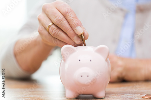 Fotografía senior woman hand putting money to piggy bank