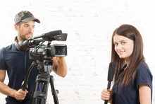 A Young Woman Journalist With A Microphone And A Cameraman
