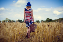 Image Of Elegant Female In Blue Hat With Retro Suitcase Walking