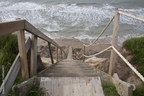 Fototapeta na wymiar Stairway to the Beach. A long wooden staircase makes its way down an unstable cliff face to the sea below.
