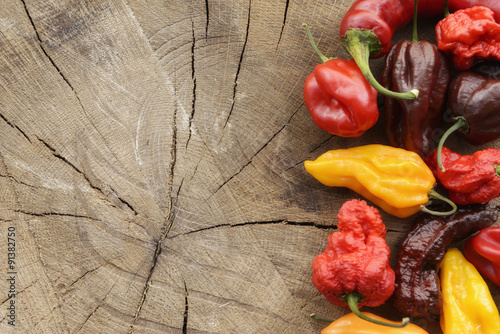 Plakat na zamówienie Various colorful hot peppers on a wooden background arranged on the side with space for content.