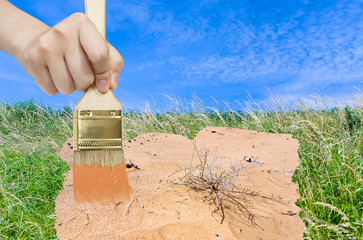 Canvas Print - hand with paintbrush paints sand in green meadow