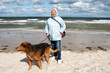 Seniorin mit Hund macht einen Spaziergang am Strand
