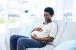 © WavebreakMediaMicro - Pregnant woman touching her belly while sitting at home