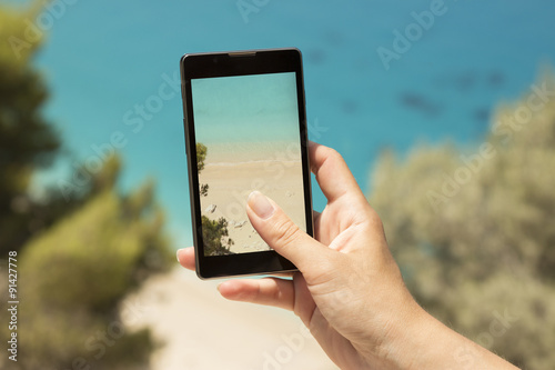Fotomural Taking a snapshot of a beautiful beach with a cellphone