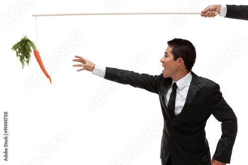 Fotomural Businessman reaching for a carrot at the end of a stick