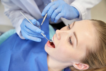 Wall Mural - close up of dentist checking female patient teeth