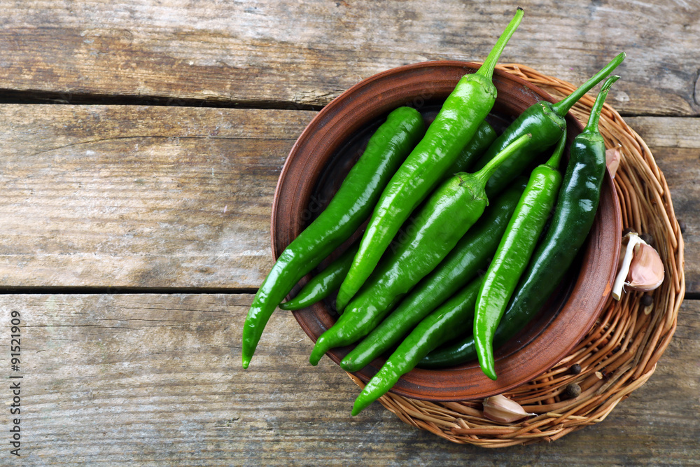Green hot peppers with garlic on wooden table close up
