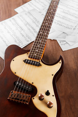 Wall Mural - Electric guitar with music notes on wooden table close up