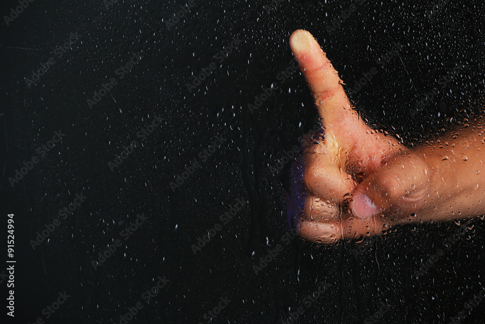 Male hand behind  wet glass, close-up
