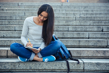 Poster - Happy female student writing notes in notepad