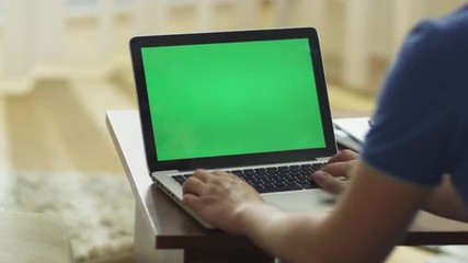 Man Using Laptop with Green Screen in Living Room.