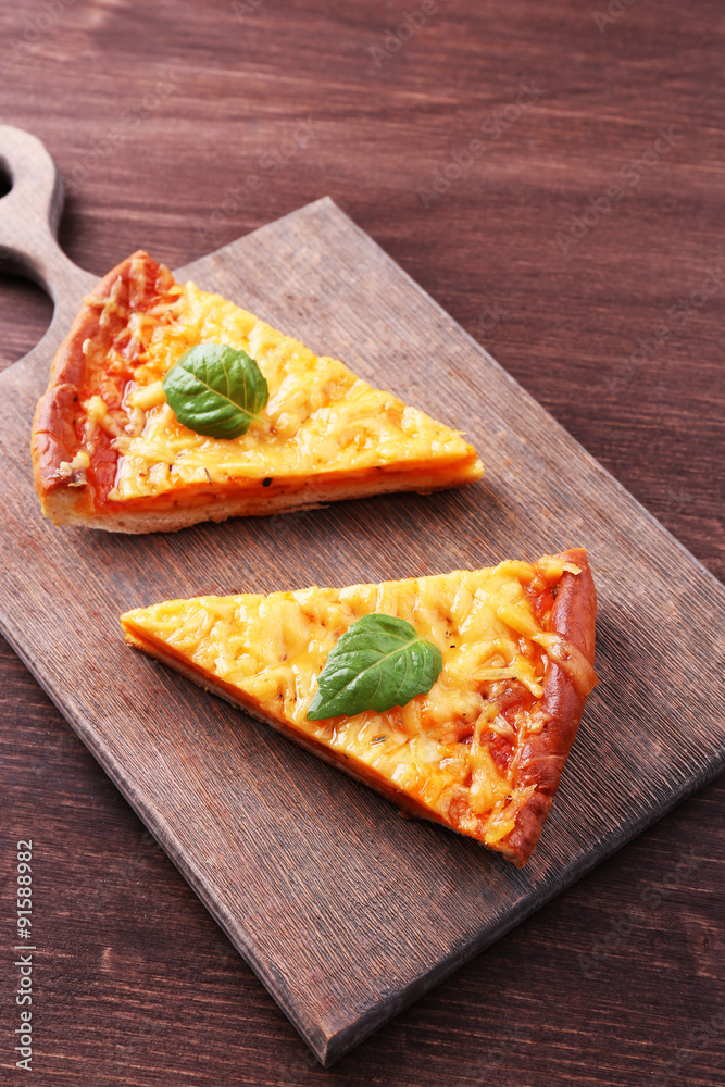 Slices of tasty cheese pizza with basil on table close up