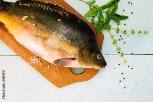 Fotografia, Obraz Raw fish (tenchе) with basil on a wooden cutting board, top vie