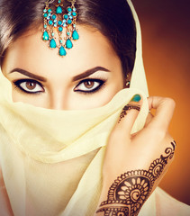 Beautiful indian woman with traditional turquoise jewels hiding her face