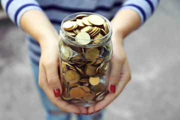 Poster - Woman holding money jar with coins outdoors