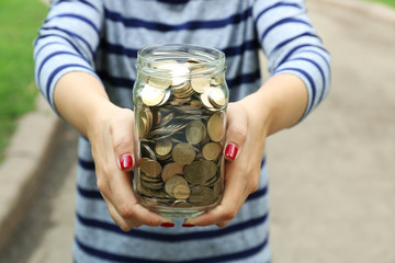 Poster - Woman holding money jar with coins outdoors