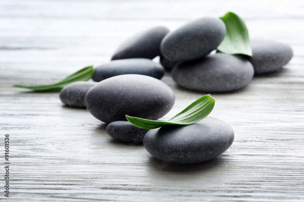 Spa stones with green leaves on wooden background