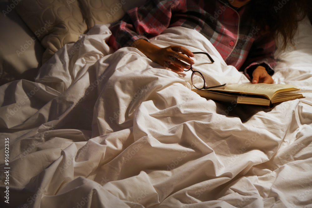 Young woman reading book in bad