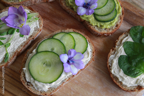 Fotografie, Obraz Green sourdough open face sandwiches with purple edible flowers