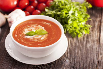 Delicious tomato soup with aromatic spices on a wooden table.